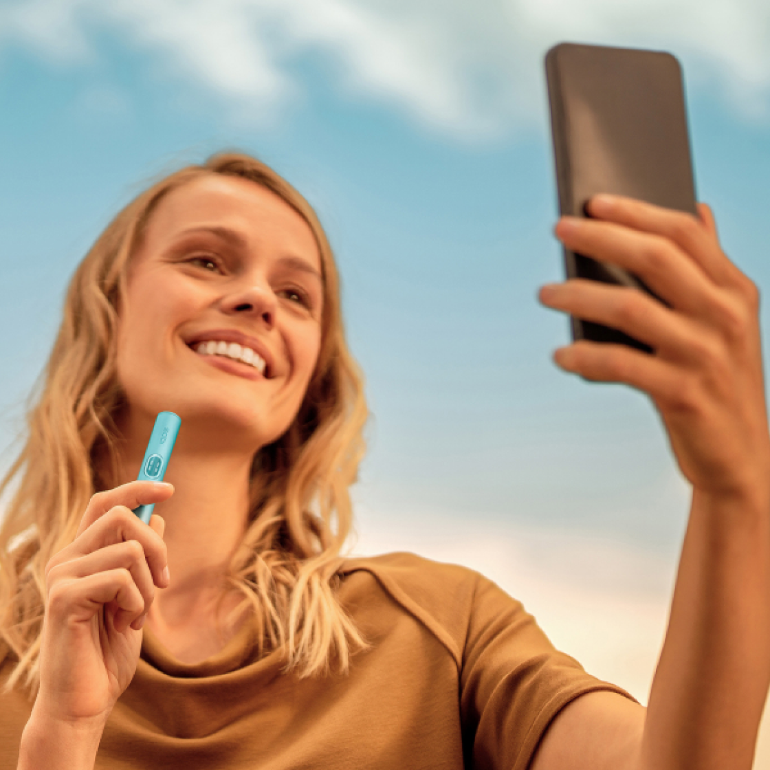 Man with phone in one hand, IQOS device in the other